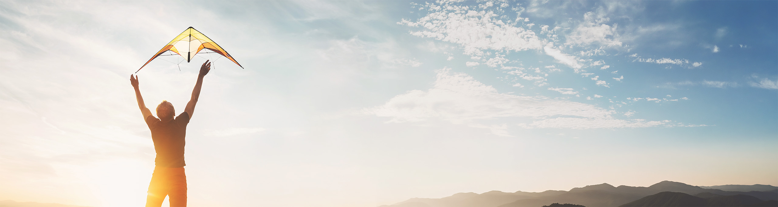 Junger Mann lässt Drachen in hellen Himmel steigen: Berufsorientierung für Jugendliche auf dem Weg zum Wunschjob.